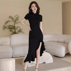 Woman in a black dress standing in a modern living room.