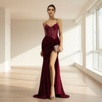 Woman wearing a burgundy evening gown with a high slit on a gray background