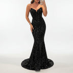 Woman in a black sequin dress taking a mirror selfie in an indoor setting.