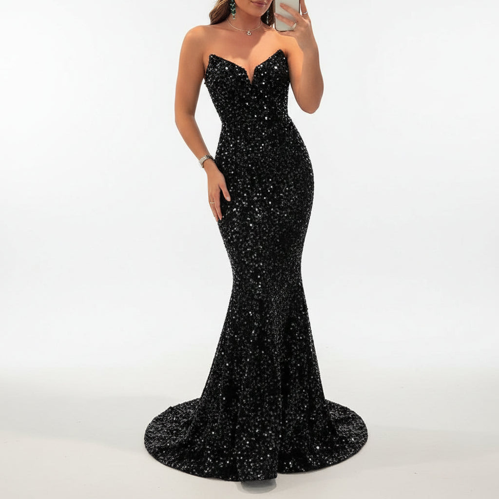 Woman in a black sequin dress taking a mirror selfie in an indoor setting.