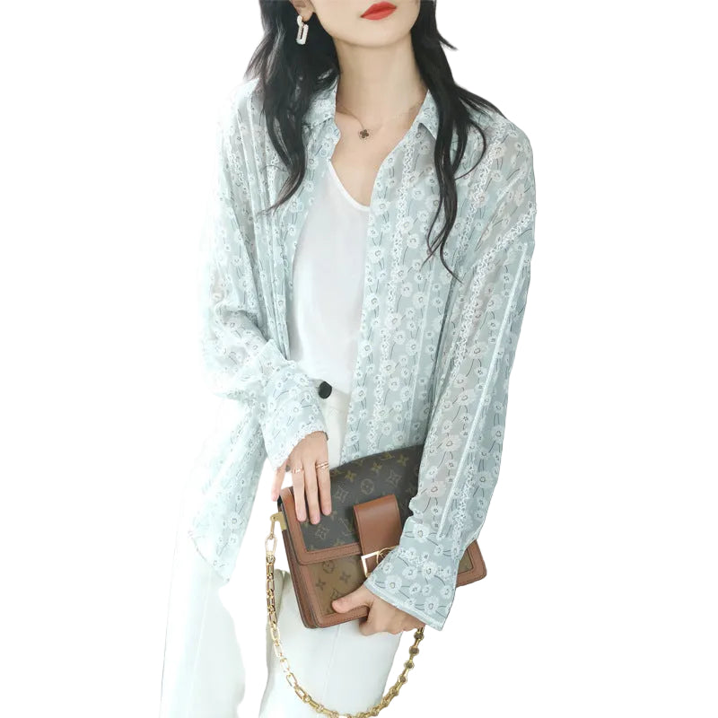 Woman holding a brown handbag with gold chain, wearing a light blue floral lace blouse.
