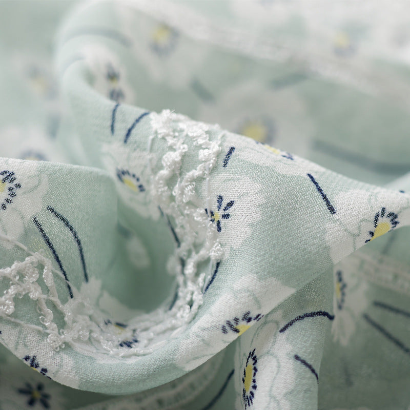 Close-up of light green fabric with floral patterns and lace details