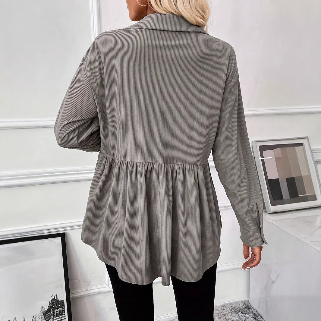 Person wearing a gray ribbed blouse in a room with white walls and framed pictures.