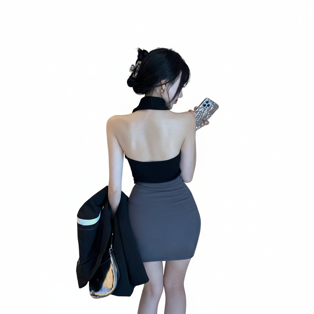 Woman in a black top and gray skirt standing in a room with a lamp and couch.