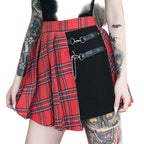 Person wearing a red plaid skirt with a black bag over it, standing against a natural background.